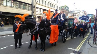 Two horses, dressed in the Easy Group's orange, pull the hearse